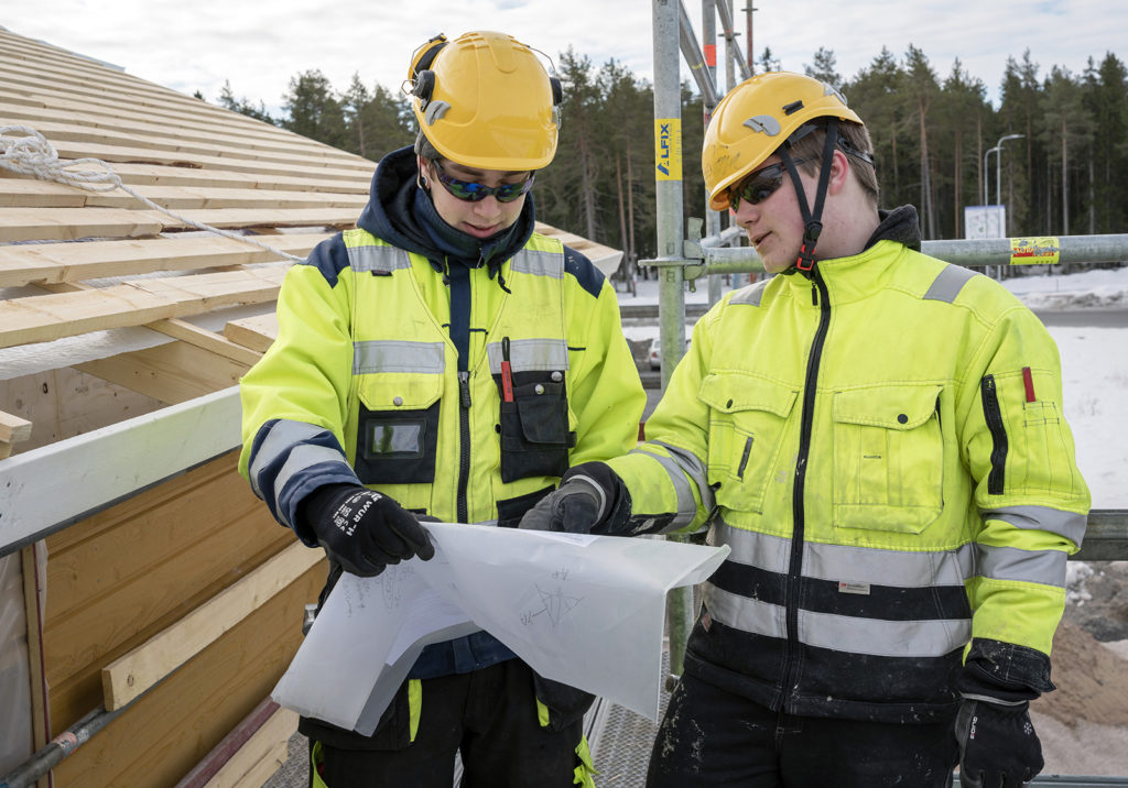 Kaksi rakennusmiestä lukee rakennuspiirustuksia.