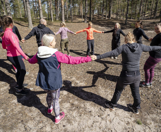 Joukko ihmisiä pitää toisiaan käsistä kiinni ympyrän muodossa.