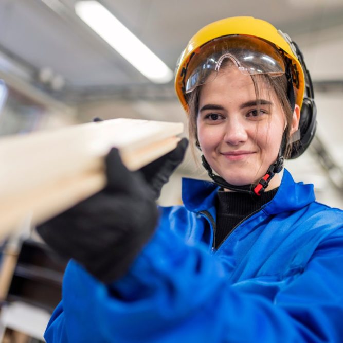 Sahaprosessinhoitaja työskentelee sinisessä haalarissa ja tarkkailee laudan suoruutta.