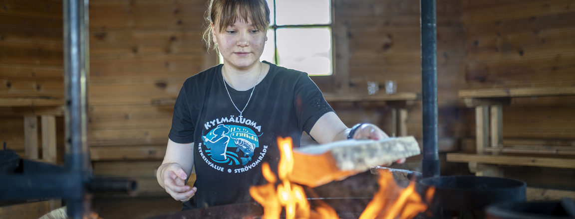 Elisa Olkkola sytyttää tulta erätuvassa.