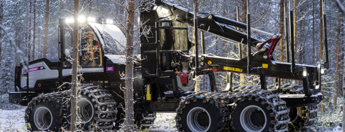 Metsäkone työssä talvisessa metsässä aamun hämärässä.