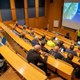 Ihmiset istuvat auditoriossa ja kuuntelevat esitystä.