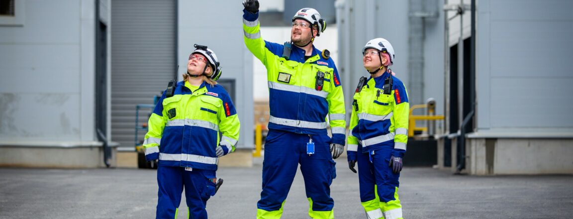 Kolme suojapukuihin varustautunutta Terrafamen työntekijää kuvattuna tehdasalueella.