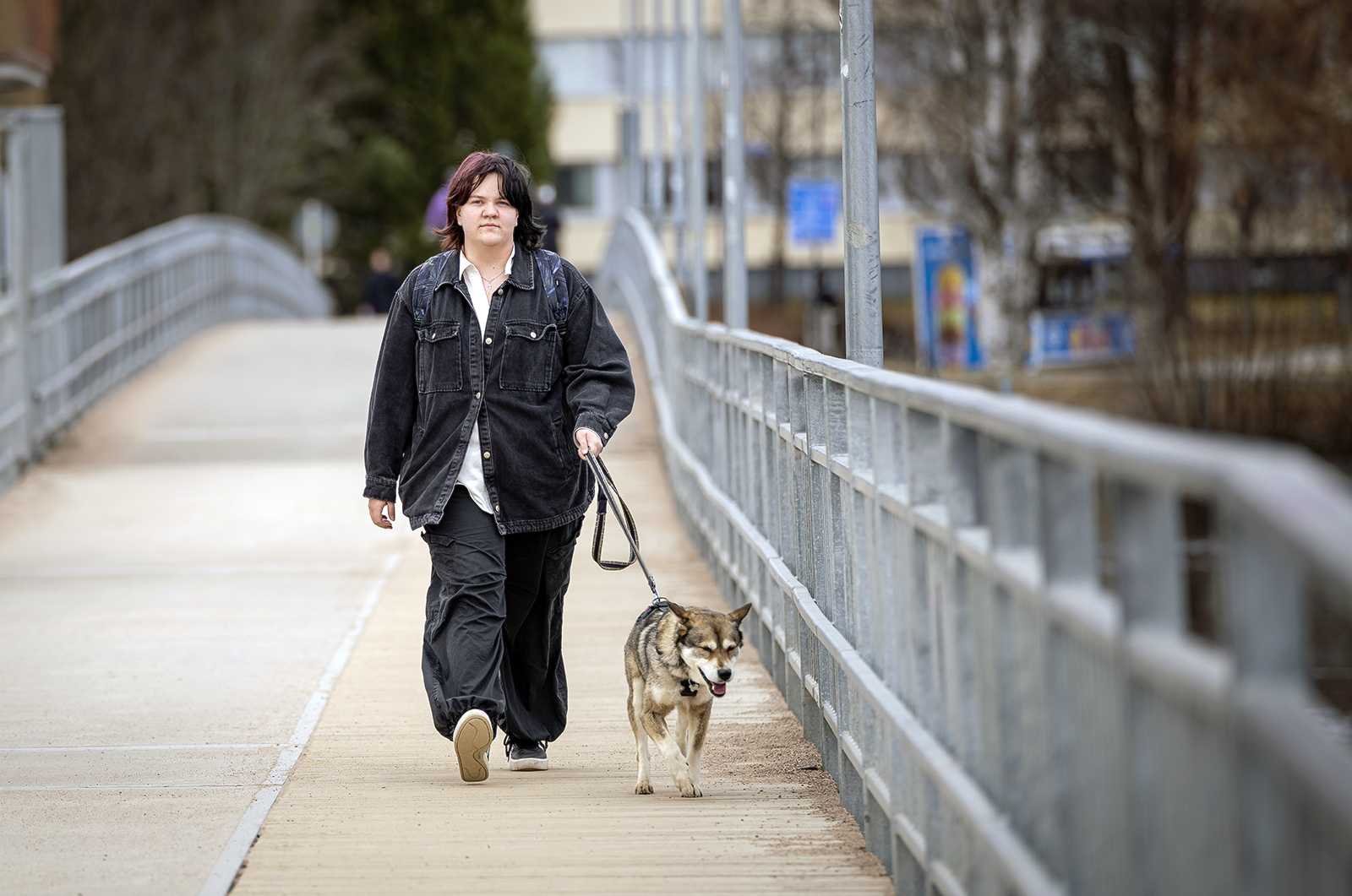 Mirella kuvattuna sillalla lenkittämässä valko-harmaata koiraa.