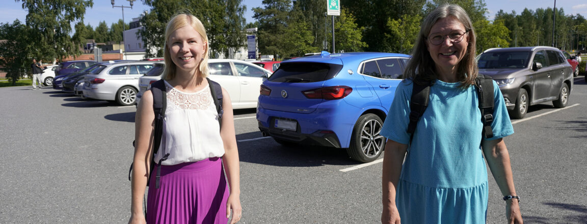 Maria Nykänen ja Pirjo Pokkinen kävelevät parkkipaikalla. Taustalla autoja.