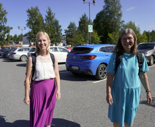 Maria Nykänen ja Pirjo Pokkinen kävelevät parkkipaikalla. Taustalla autoja.