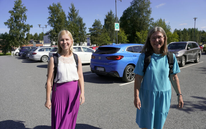 Maria Nykänen ja Pirjo Pokkinen kävelevät parkkipaikalla. Taustalla autoja.