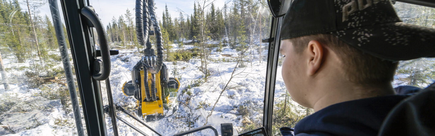 OSAOn metsäalan opiskelija kuvattuna metsäkoneen ohjaamossa.